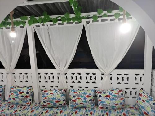 a bed in a room with curtains and pillows at Nyumba Tulivu in Watamu