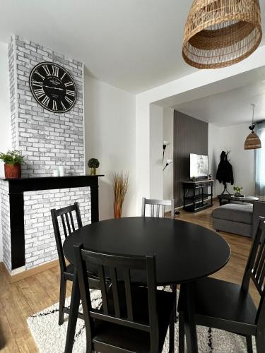 un salon avec une table et une horloge sur un mur de briques dans l'établissement Appartement Cosy Valenciennes, à Marly