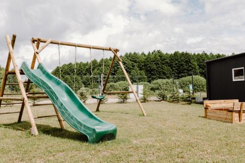a playground with a green slide in a yard at Regielskie Chaty in Regiel