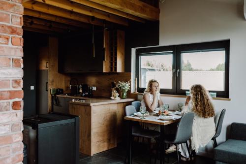 two women sitting at a table in a kitchen at Regielskie Chaty in Regiel