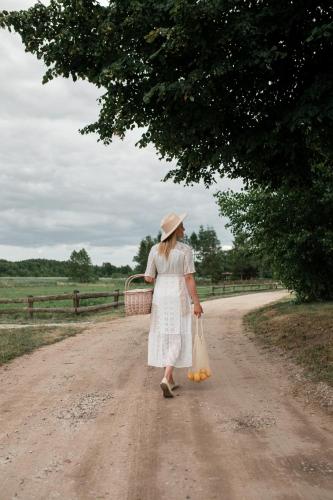 a woman in a white dress walking down a dirt road at Regielskie Chaty in Regiel
