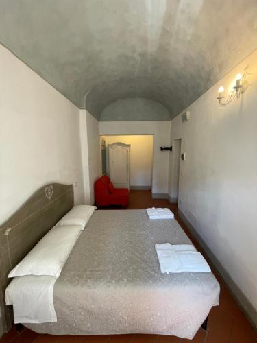a bedroom with a bed and a red chair at BonConvento Guesthouse - HiTuscany in Pisa