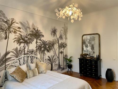 a bedroom with a bed with palm trees on the wall at Appartement niçois au coeur du triangle d'or in Nice