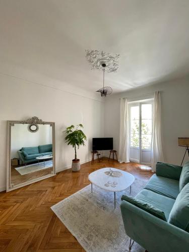 un salon avec un canapé bleu et un miroir dans l'établissement Appartement niçois au coeur du triangle d'or, à Nice