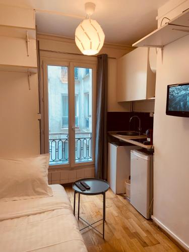 Cette petite chambre comprend un lit, une table et une fenêtre. dans l'établissement Studio Anvers, à Paris