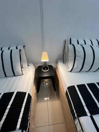 two beds in a room with a side table with a lamp at 7 STAY#2 - 1 Room for 3 Pax at Kuala Berang -Best Travelers Stay in Kuala Berang
