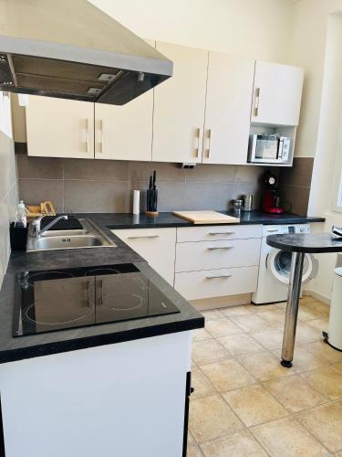 une cuisine avec des armoires blanches et un évier dans l'établissement Appartement T4 Intra-muros avec terrasse, à Avignon