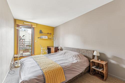 une chambre avec un lit avec un mur jaune dans l'établissement Appartement duplex dans le Saint Lambert by Weekome, à Paris