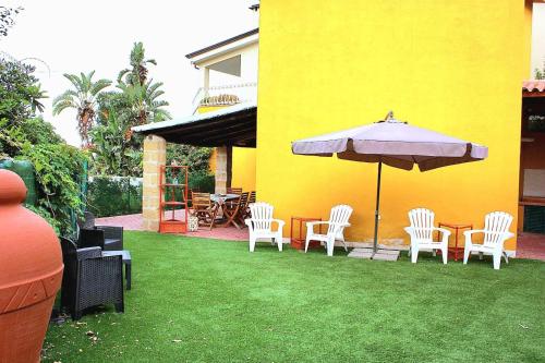 a patio with a table and chairs and an umbrella at Villetta vista mare a Praialonga in Le Castella
