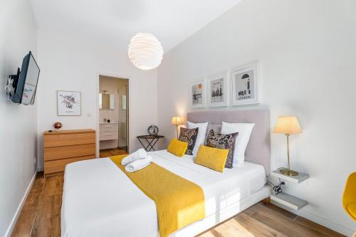 - une chambre blanche avec un grand lit et des oreillers jaunes dans l'établissement Nice Renting - ROSSETTI - Modern Haven Heart of Old Nice, à Nice
