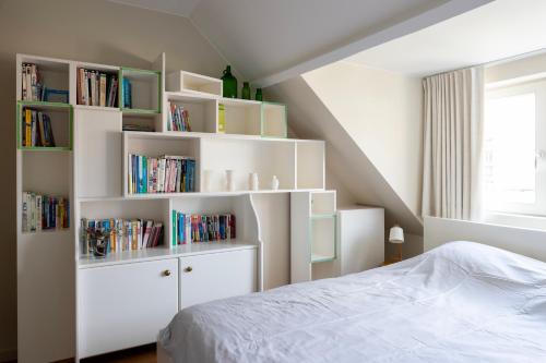 a bedroom with white book shelves and a bed at 3 Kings in Bruges