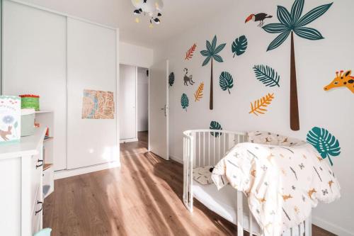 une chambre d'enfant avec un berceau blanc et des plantes sur le mur dans l'établissement 80m2 avec salle de sport JO, à Saint-Denis