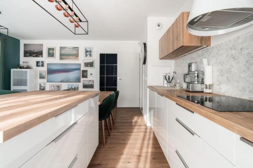 une cuisine avec des armoires blanches et des comptoirs en bois dans l'établissement 80m2 avec salle de sport JO, à Saint-Denis