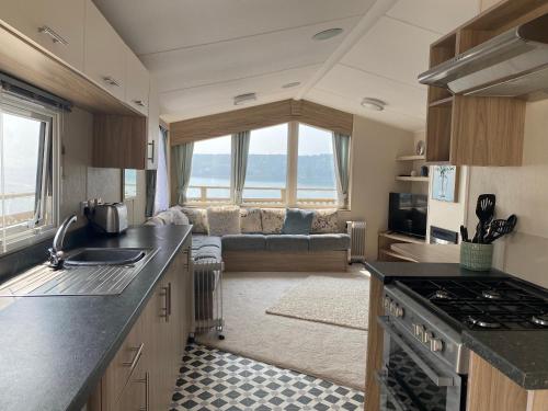 a kitchen and living room with a couch at Static Caravan at Lydstep Beach in Tenby