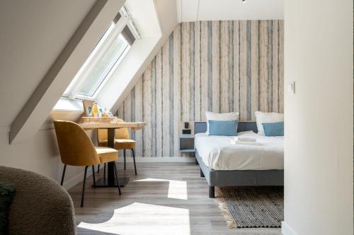 ein Schlafzimmer mit einem Bett und einem Tisch und einem Fenster in der Unterkunft Hello Zeeland - Appartement Duno Lodge M in Oostkapelle
