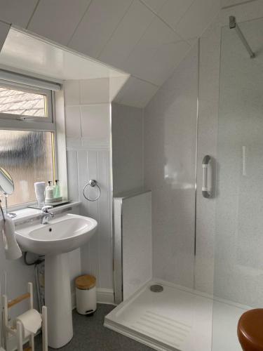 a white bathroom with a sink and a shower at Clune House B&B in Newtonmore