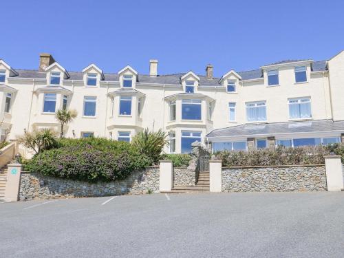 a large white house with a stone wall at Bethan Apartment in Trearddur