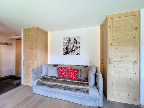 a living room with a blue couch with a red pillow at Plein Ciel 118 **** in Verbier
