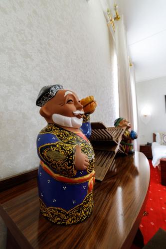 a statue of a man eating a hot dog on a table at Qibla Tozabog in Khiva