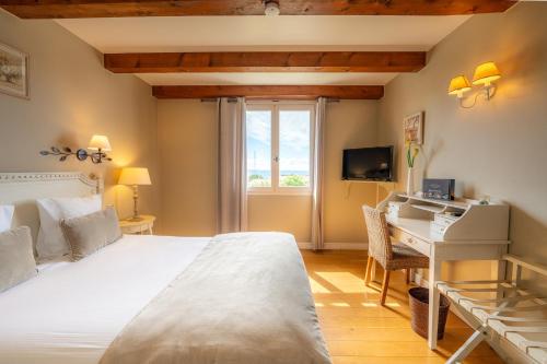 a bedroom with a bed and a desk and a window at Hôtel Le Pré Saint Michel in Manosque