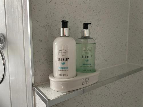 two bottles of detergent sitting on a shelf in a bathroom at Clune House B&B in Newtonmore