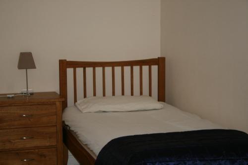 a bed with a wooden headboard and a dresser at BCC Loch Ness Hostel in Bearnock