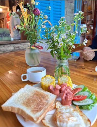 Sapa Jungle Homestay في سابا: طبق من الطعام مع الخبز المحمص والفواكه على طاولة