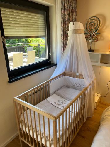 a crib with a canopy in a room with a window at Die Landhausvilla in Unterach am Attersee in Unterach am Attersee