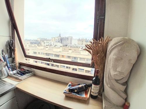 une fenêtre avec une bouteille de vin sur un bureau dans l'établissement jolie studio à paris 12 em, à Paris