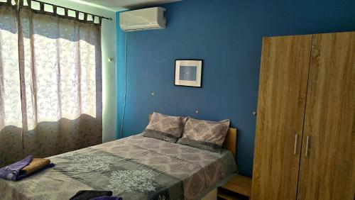 a bedroom with a bed and a blue wall at Grand Apartment Pomorie in Pomorie