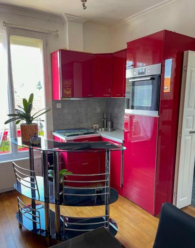 Il comprend une cuisine équipée de placards rouges et d'un réfrigérateur rouge. dans l'établissement Appartement en duplex entre Paris et Versailles, à Chaville