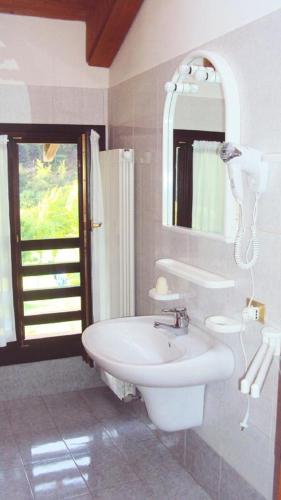 a white bathroom with a sink and a mirror at Casa Felicita in Ledro