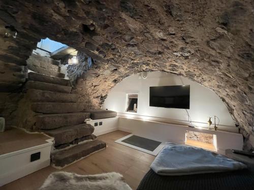 ein Wohnzimmer mit einer Steinmauer und einem TV in der Unterkunft La Chaumière in Saulxures-sur-Moselotte