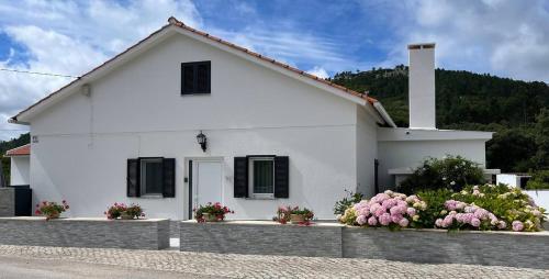 a white house with flowers in front of it at Location d'une maison traditionnel dans un village in Bouceiros