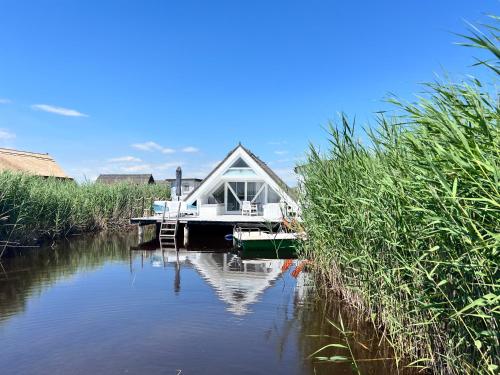 a house on a river with a boat in the water at Seehütte Neusiedlersee - Strandhaus, Elektroboot inklusive in Rust