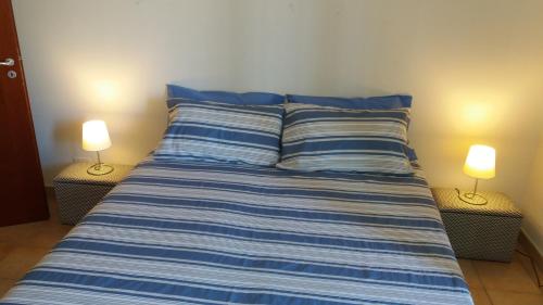 a bed with blue and white striped sheets and two lamps at Ionio in Reggio Calabria