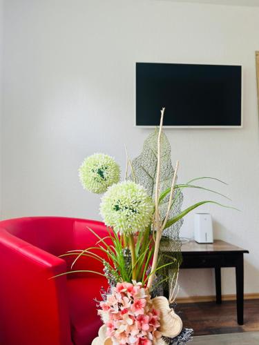 a red chair with a vase of flowers on a table at Sollstedt Ferienwohnung in Sollstedt