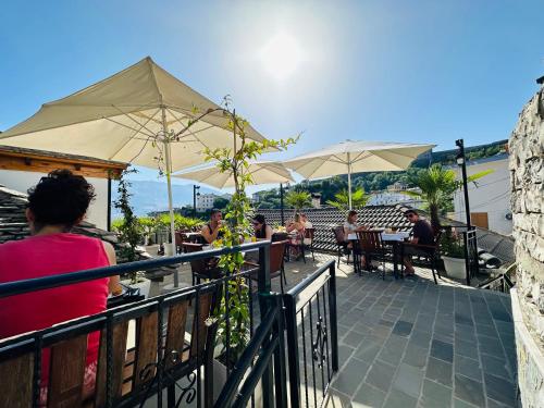 a group of people sitting at a restaurant with umbrellas at Kore Guest House in Gjirokastër