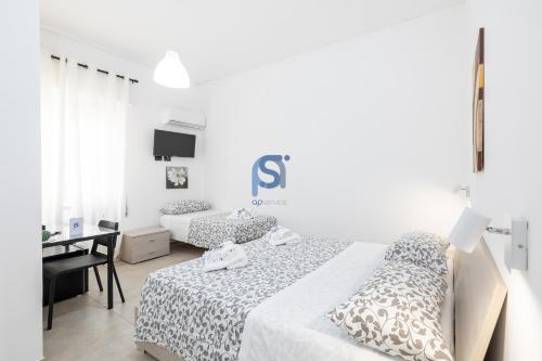 a white bedroom with two beds and a desk at Al Posto Giusto - Self Check in in Cefalù