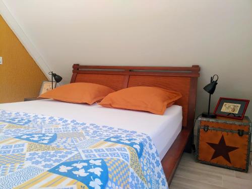 a bedroom with a bed with orange pillows on it at Eskal Péi - Auberge de Jeunesse & Chambres d'hôtes in Étang-Salé