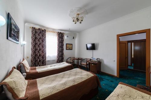 a hotel room with two beds and a television at Qibla Tozabog in Khiva