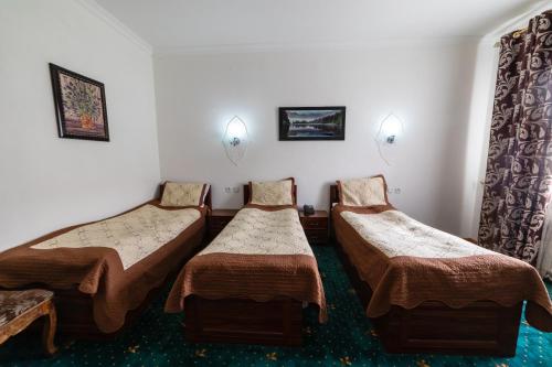a room with three beds in a room at Qibla Tozabog in Khiva