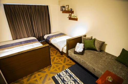 a hotel room with two beds and a couch at e-stay ebisu in Osaka
