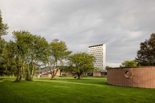 a park with a brick wall and a tall building at Højhuset Kulturhotel in Herning