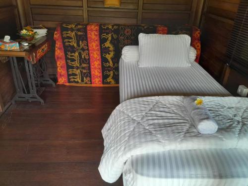 a room with two beds and a table with a table at Ketewel Bed & Breakfast Yoga Room in Ketewel