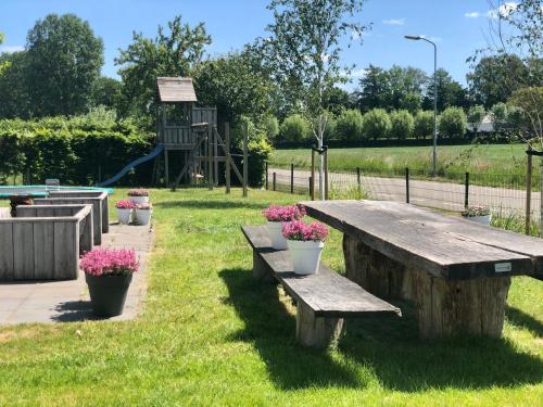 a wooden bench in a park with flowers on it at De Slaapfabriek vakantiehuis en trainingslocatie in Teuge