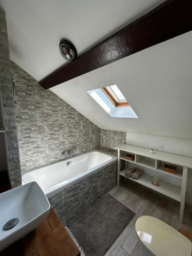 La salle de bains est pourvue d'une baignoire et d'une lucarne. dans l'établissement Appartement à 10 min de Paris - Train, Métro, à Noisy-le-Sec