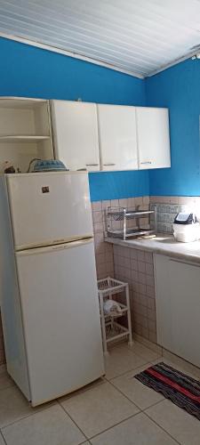 a kitchen with a white refrigerator and blue walls at Pousada Canto dos Passaros in Chapada dos Guimarães