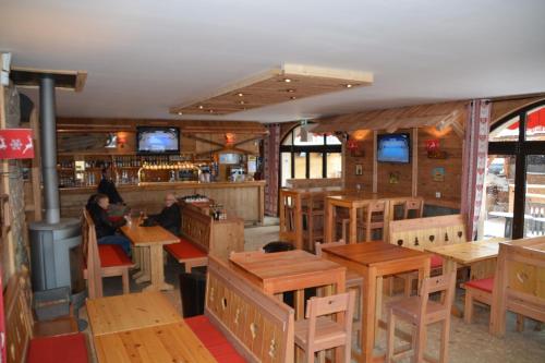 a restaurant with wooden tables and people sitting at tables at Hôtel Alpis Cottia in Montgenèvre