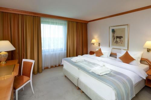 a hotel room with a large bed and a desk at Maritim Airport Hotel Hannover in Hannover